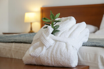 White cotton bathrobe with olive tree twig on the bed  in hotel room. Tourism, hotels, hospitality...