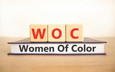 WOC women of color symbol. Concept words WOC women of color on beautiful wooden blocks and book. Beautiful white background. Business WOC women of color social issues concept. Copy space. - obrazy, fototapety, plakaty