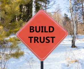 Build trust symbol. Concept words Build trust on beautiful red road sign. Beautiful forest snow blue sky background. Business and build trust concept, copy space.