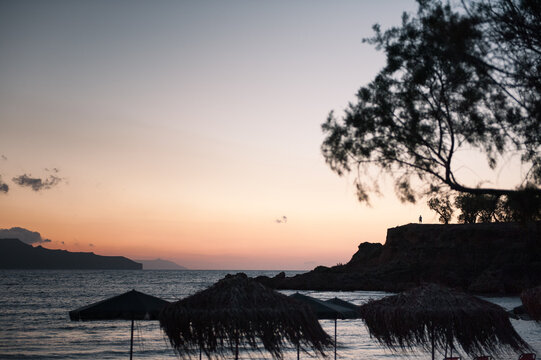 a silhouette of a person standing on a cliff by the sea in a sunset in Crete 