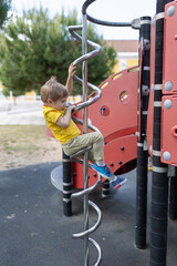 A young boy is climbing a spiral slide - children's playground