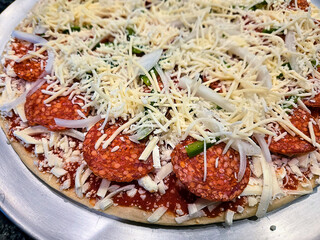 Shredded mozzarella cheese with pepperoni, green peppers, and onions on a thin crust pizza - 798154907