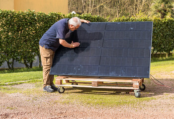 Senior man with photovoltaic solar panel in the garden.