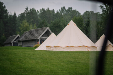Dobele, Latvia - August 18, 2023 - A canvas bell tent on a rainy day, with pine trees and rustic...