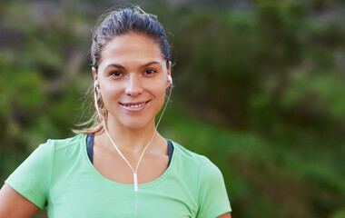 Runner, portrait and happy woman listening to music for exercise or workout in park, woods or...