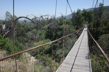 Pirque, Chile - 25 Nov, 2024: A suspension footbridge across a stream in the Maipo Valley,...