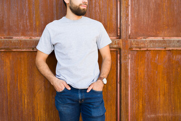 Confident young hispanic man poses against a rustic brown backdrop, ideal for showcasing fashion or casual clothing designs