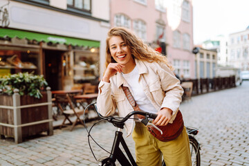 Fototapeta na wymiar Happy woman riding bicycle at the city street outdoor. Active lifestyle. The concept of nature.