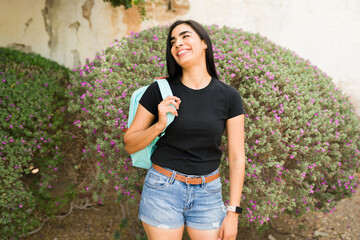 Happy hispanic woman in a black t-shirt mockup poses against a floral backdrop, ideal for fashion and apparel designs
