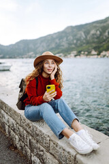Young woman with phone on the embankment. Tourist during holidays. Lifestyle, travel, nature, active life.