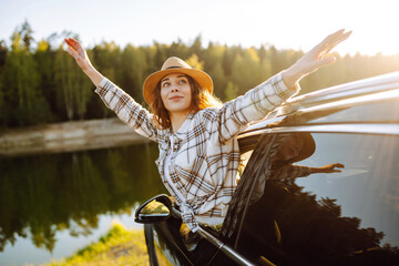 Relaxed woman leaning out car window during summer trip.  Lifestyle, travel, tourism, nature,...