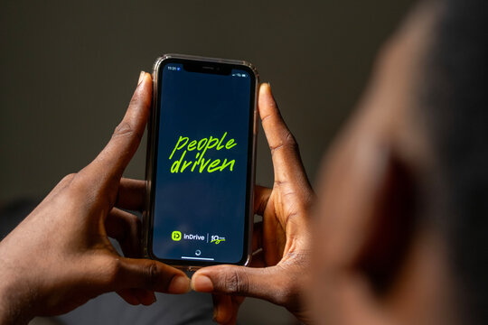 african man using Indrive apps on on Apple smartphone, guy trying to book a drive from his comfort zone. Indrive is sharing-economy service for urban transport. Abuja, F.C.T, Nigeria - 26 April 2024