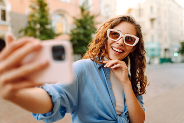 Cheerful female tourist clicking selfie pictures via cellphone front camera. Lifestyle, travel, tourism, active life.