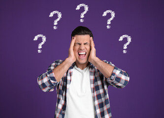 Amnesia. Stressed man and question marks on purple background