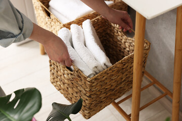 Woman holding storage basket with towels indoors, closeup