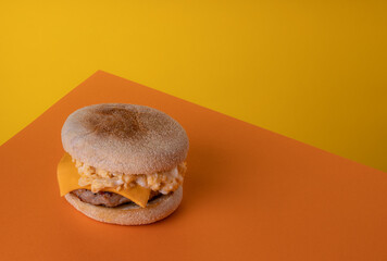 Scrambled Egg and Sausage Breakfast Muffin on a Funky Yellow and Orange Background