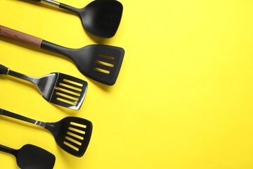 Different spatulas on yellow background, flat lay. Space for text - obrazy, fototapety, plakaty