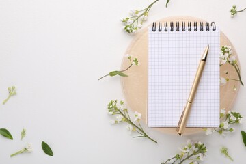 Guest list. Notebook, pen and beautiful spring tree blossoms on white background, flat lay. Space...