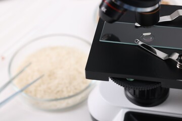 Food quality control. Glass slide with rice grain under microscope on table, closeup