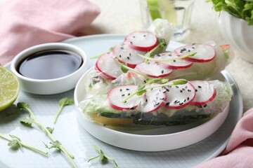 Delicious spring rolls, microgreens and soy sauce on table, closeup