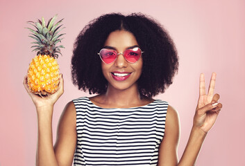 Peace sign, portrait and black woman with pineapple, studio or detox on pink background. Health,...