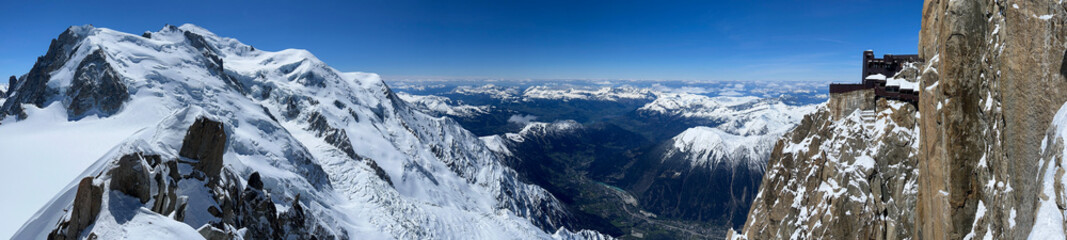 Fototapeta na wymiar Haute-Savoie, France, 04-25-2024: panoramic view of L’Aiguille du Midi (Needle at midday), the highest spire (3.842 m) of the Aiguilles de Chamonix with the Mont Blanc massif peaks and Chamonix Valley