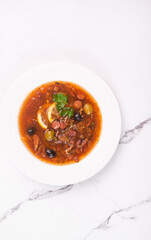 Vegetable soup with Solyanka tomatoes in a white plate