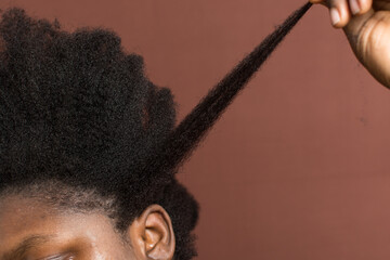 woman stretching her curly hair to emphasize shrinkage, 4c hair stretched to show shrinkage