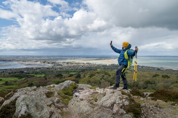 Happy hiker enjoying nature, filming and taking selfies with mobile phone to share on social networks