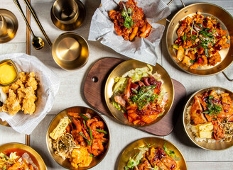 Korean food variety Roast pig feet, Korean Spicy Chicken, Grilled Chicken Leg Bento, Grilled Squid Ring, Sweet and spicy fried chicken with spoon and chopsticks served in golden dish side view