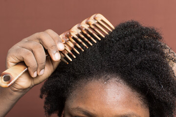 Combing black afro curly hair with shrinkage, using a wide tooth comb to detangle wet Type 4c hair