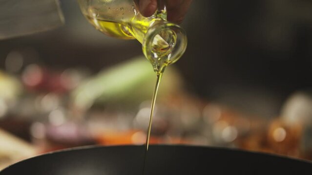 Chef pouring olive oil on a pan hot pan
