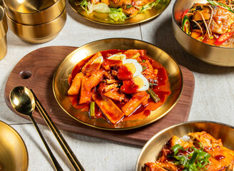 Spicy rice cake with egg with spoon and chopsticks served in golden dish isolated on wooden board side view of honk kong food