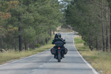 A man and woman are riding a motorcycle down a country road