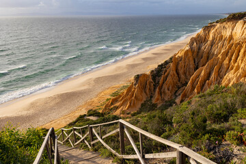 A beach with a wooden walkway leading to the water
