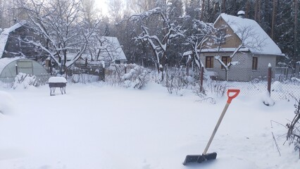 After a snowfall snow lies on the ground and tree branches in the forest and garden. A shovel in...