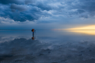 Solitary photographer stands on a reflective water surface, capturing the breathtaking contrast...