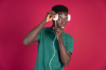 A man in a green shirt is wearing headphones and holding a cord