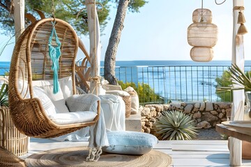 A coastal-themed terrace setup with a wicker swinging chair nestled within a breezy outdoor space, overlooking a tranquil seascape - obrazy, fototapety, plakaty