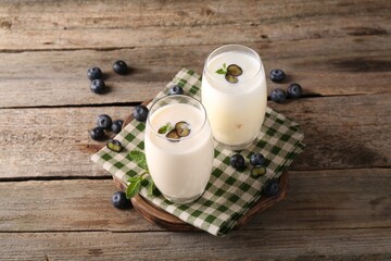 Composition with tasty yogurt in glasses and blueberries on wooden table