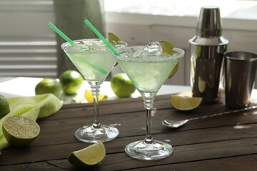 Delicious Margarita cocktail in glasses and lime on wooden table, closeup