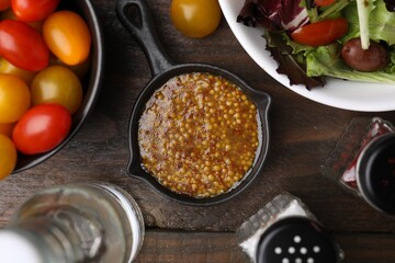 Tasty vinegar based sauce (Vinaigrette), salad, tomatoes and spices on wooden table, flat lay
