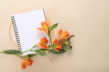 Guest list. Notebook and beautiful flowers on beige background, top view. Space for text