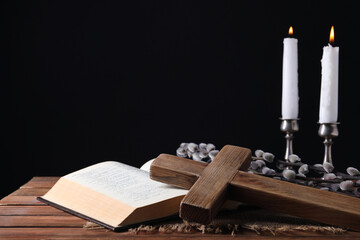 Burning church candles, cross, Bible and willow branches on wooden table