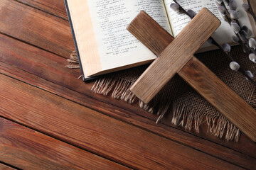 Cross, Bible and willow branches on wooden table, flat lay. Space for text