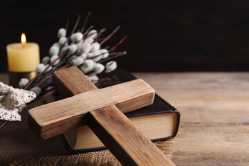 Cross, Bible and willow branches on wooden table, closeup. Space for text
