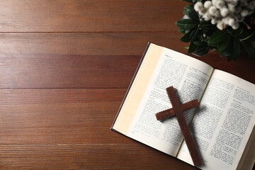 Bible, plant with willow branches and cross on wooden table, flat lay. Space for text