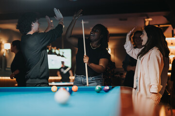 A group of joyful friends celebrate together at a pool table in a bar, enjoying a fun night out...