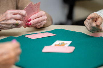 Active retirement, group of elderly women having fun playing cards game at nursing home. High quality photography.