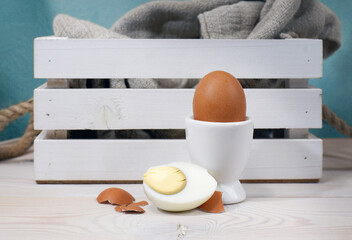 Egg at the egg-cup and half a boiled egg. Eggs in a brown shell on a wooden table